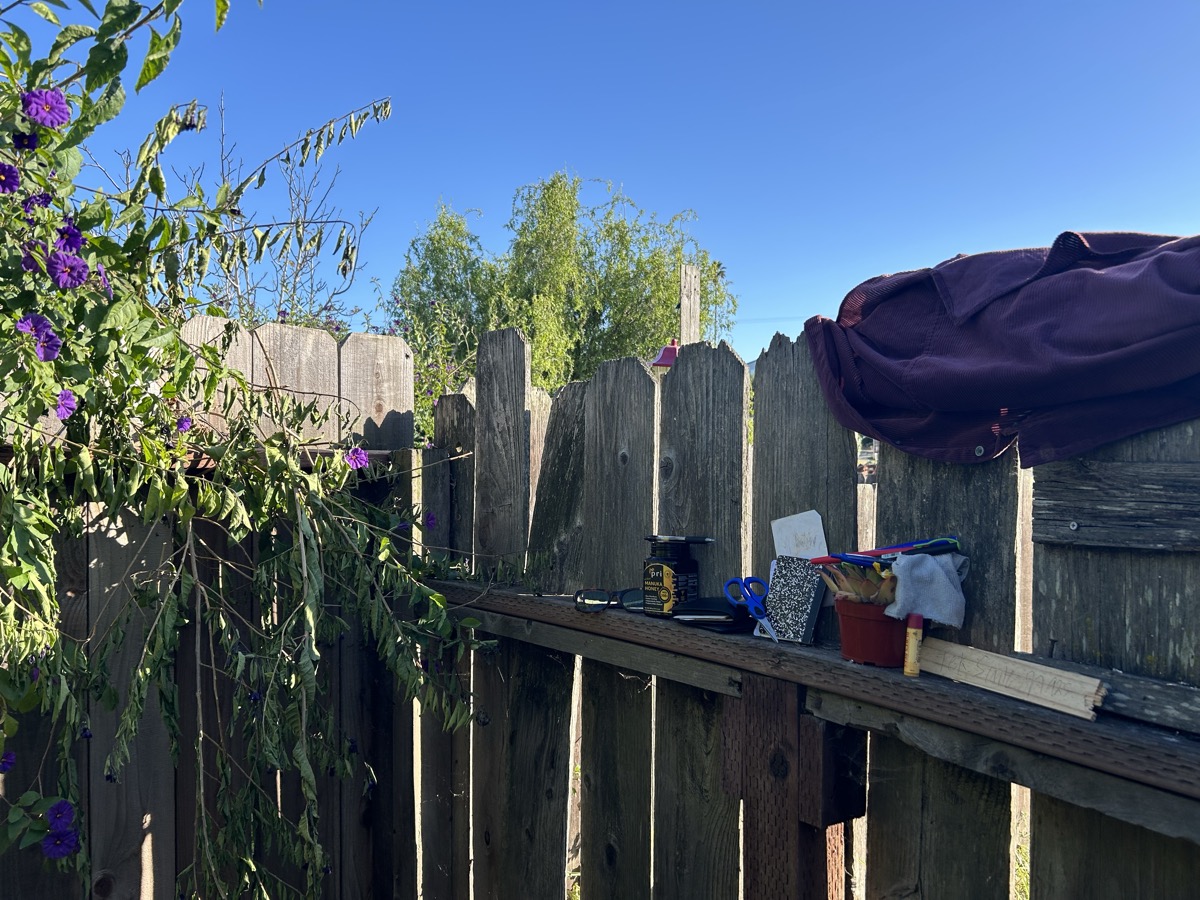 KenshoTek Field Office — Wooden fence desk, purple flowers, blue sky, notebooks