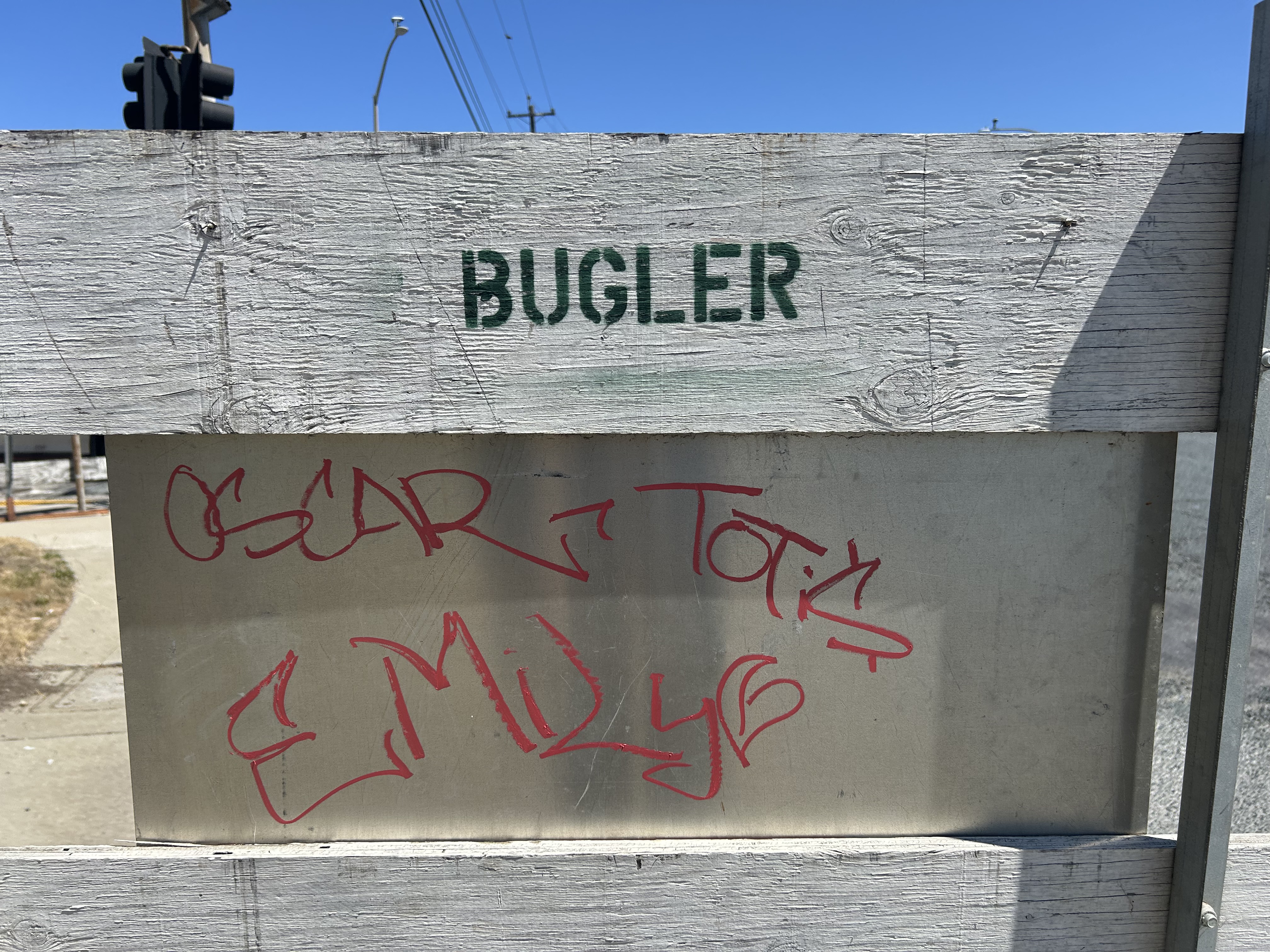 BUGLER stenciled on weathered white fence — red graffiti tags OSCAR TONY EMILY below — East Bay street scene — 925