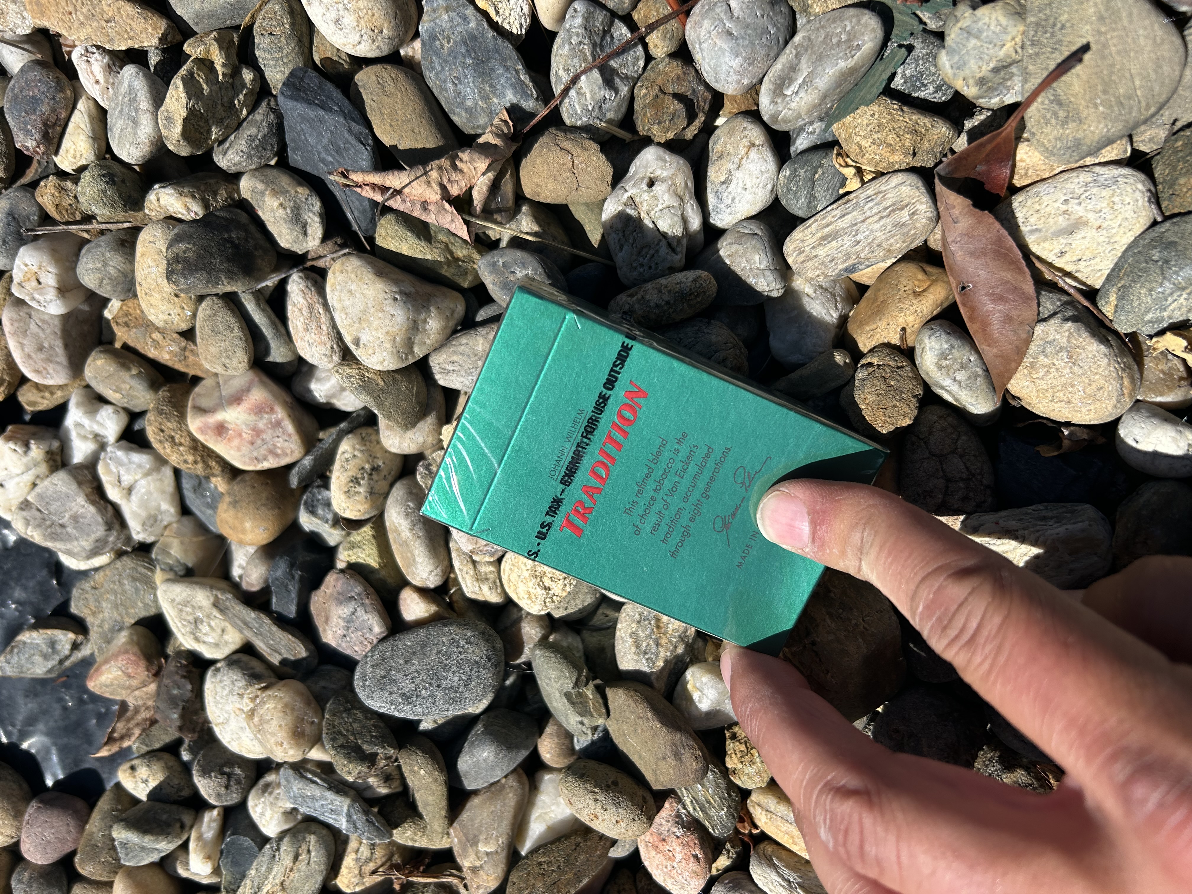 Johann Wilhelm Von Eicken TRADITION menthol cigarettes — green pack held over river rocks — Tara Hills Dr — El Sobrante — East Bay 925