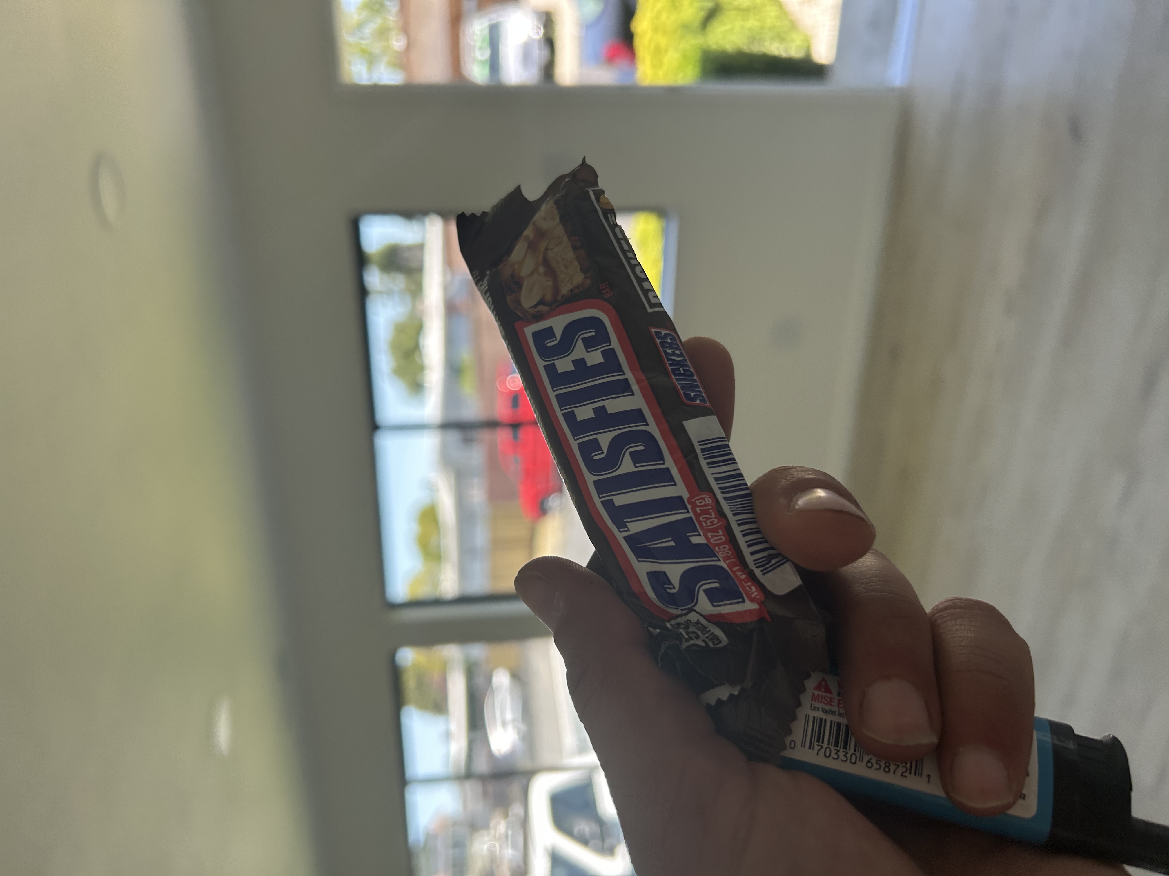 Snickers bar showing SATISFIES wrapper, held in the East Bay