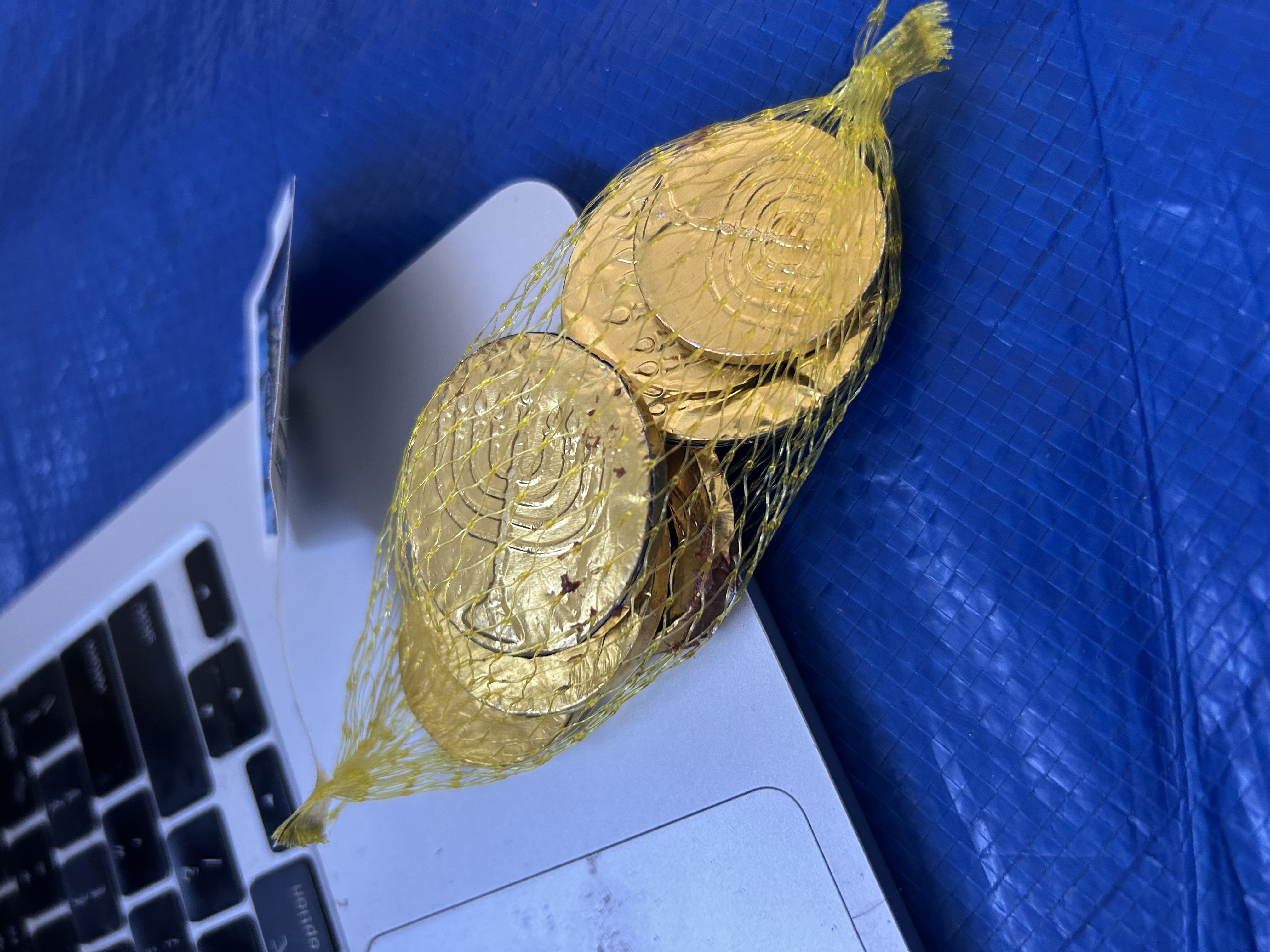 Gold chocolate coin tokens on a MacBook