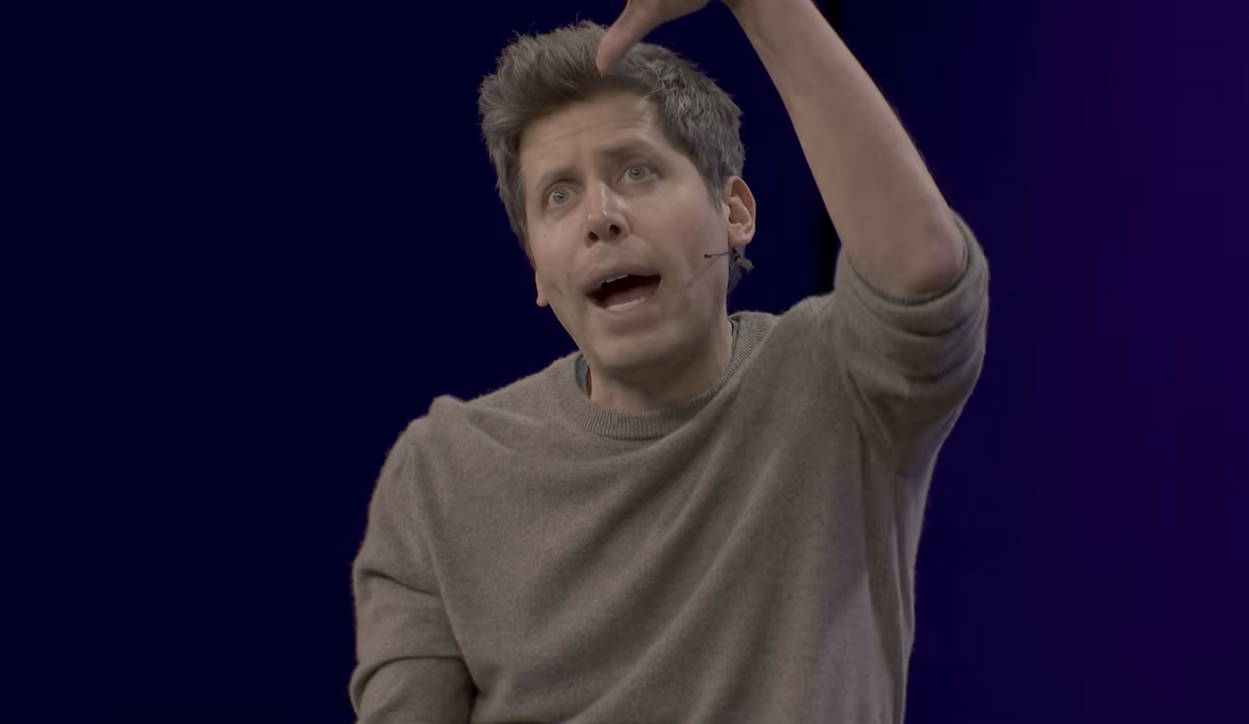 Sam Altman — arm raised overhead, eyes wide, mouth open, full vision-cast mode